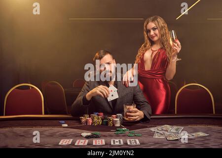 Charmante wohlhabende Paare spielen Poker in einem Casino. Stockfoto