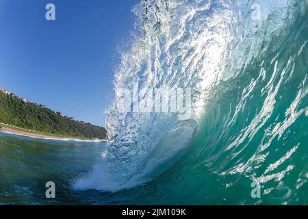 Ocean Wave Schwimmen Nahaufnahme hinterleuchtete Texturen aufrecht hohl krachende Wasserkraft auf flachen Riffen am frühen Morgen. Stockfoto