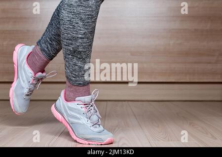Passen Sie das weibliche Bein in den Sportschuhschritt an Stockfoto