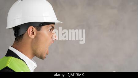 Junger arabischer Architekt Inspektor Mann trägt Baumeister Sicherheitshelm frustriert Schreien vor Wut, verrückt und schreiend, Wut Konzept. Banner Stockfoto
