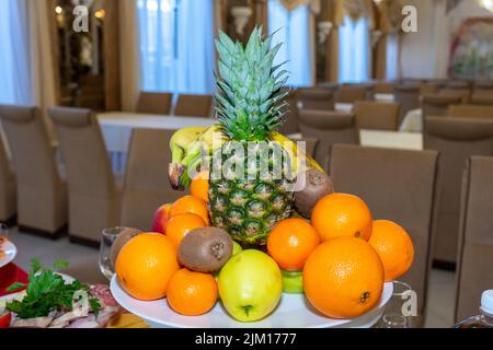 Frisches Gemüse und Obst auf einem weißen Teller. Obstschale auf einem Teller in einem Restaurant. Stockfoto