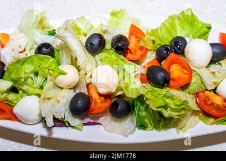 Isolierter Teller mit Salat auf weißem Hintergrund. Salat aus Wachteleiern, Gemüse, Tomaten und Oliven. Stockfoto