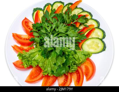 Tomaten, Gurken, Paprika in Scheiben geschnitten und mit Petersilie und Salat garniert. Teller Mit Frischem Gemüse. Isolieren Stockfoto