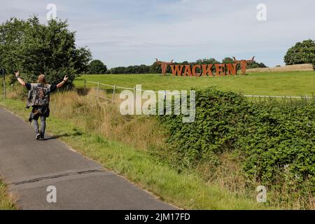 Wacken, Deutschland. 04. August 2022. Ein Metallfan geht an einem Zeichen von WOA - Wacken Open Air vorbei. Das WOA gilt als das größte Heavy Metal Festival der Welt. Quelle: Frank Molter/dpa/Alamy Live News Stockfoto