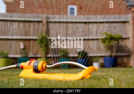 In Basingstoke, Hampshire, wird ein Gartenregner verwendet, um Gras zu bewässern. Das erste Schlauchleitungsverbot des Jahres beginnt am Freitag in Hampshire und der Isle of Wight. Die Maßnahmen zur Eindämmung des Wasseraufwandes kommen, nachdem England von November 2021 bis Juli seit 1976 den trockensten acht-Monats-Zeitraum erlebt hat, als ein Großteil des Landes unter extremer Dürre zu kämpfen hatte. Bilddatum: Donnerstag, 4. August 2022. Stockfoto