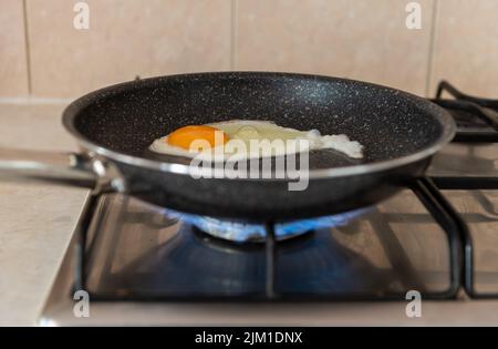 Eine Bratpfanne auf einem Herd, der Gas verbrennt. Konzept der steigenden Energieverbrauchskosten. Energiekrise. Stockfoto