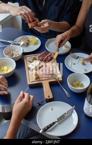 Wurstwaren und Käseplatten, Rotwein, Snacks und Menschenhände Stockfoto