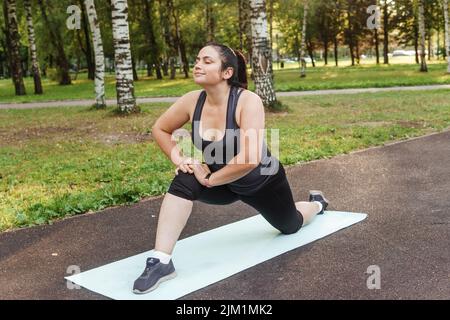 Eine charmante Brünette Frau plus-Größe Körper positiv praktiziert Sport in der Natur Stockfoto