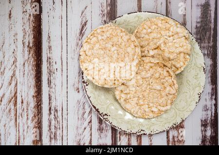 Ein runder Reiskracker auf einem rustikalen Holztisch. Speicherplatz kopieren. Gesunde, natürliche Nahrung. Vegane Küche. Draufsicht Stockfoto