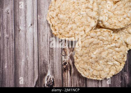 Ein runder Reiskracker auf einem rustikalen Holztisch. Speicherplatz kopieren. Gesunde, natürliche Nahrung. Vegane Küche. Draufsicht Stockfoto