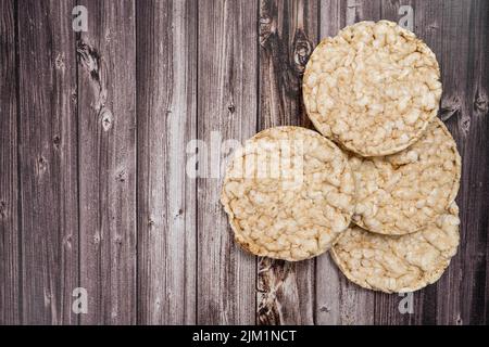 Ein runder Reiskracker auf einem rustikalen Holztisch. Speicherplatz kopieren. Gesunde, natürliche Nahrung. Vegane Küche. Draufsicht Stockfoto