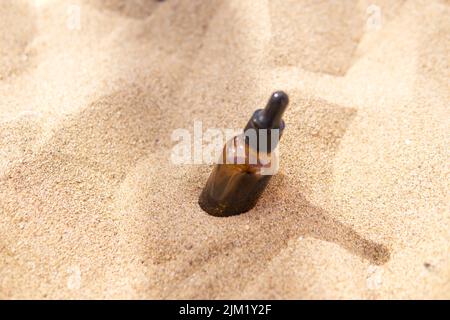 Kosmetisches Serum in einer Glasflasche mit einer Pipette im Sand Stockfoto