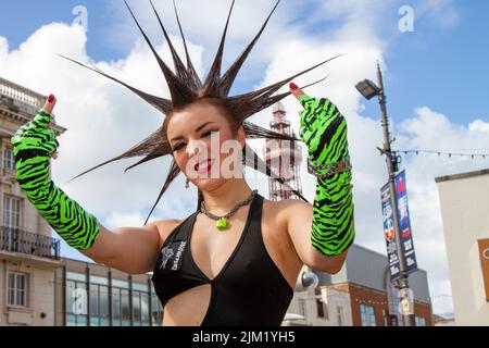 Blackpool, Lancashire, Großbritannien. 4. August 2022. Erin Micklow, Schauspielerin der amerikanischen sag-AFTRA, Stylistin der Garderobe, Moderator von YouTuber Influencer. Punk-Subkultur, Ideologien, Mode, mit Mohican gefärbten Frisuren und Farbstoffen beim Punk Rebellion Festival in den Winter Gardens. Ein Protest gegen konventionelle Einstellungen und Verhaltensweisen, ein Zusammenprall von Anti-Establishment-Kulturen, Mohawks, Sicherheitsnadeln und eine Menge Haltung in der Küstenstadt, da Punks, die das jährliche Rebellion Rock Music Festival in den Wintergärten besuchen, mit traditionellen Urlaubern Seite an Seite stehen. Stockfoto