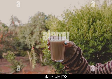 Person, die ein Glas Latte in der Hand hält Stockfoto