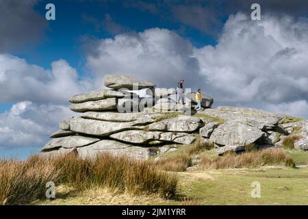Wanderer auf den riesigen Platten eines Granitfelsenstapels, der durch Gletscheraktionen auf dem Gipfel des Stowes Hill auf Bodmin Moor in Cornwall gebildet wurde. Stockfoto