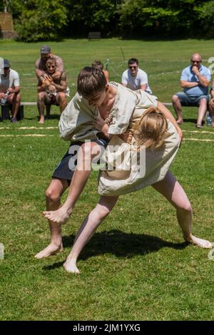 Ein junges Mädchen im Teenageralter, das mit einem Jungen kämpft, der beim Grand Cornish Wrestling Tournament in St. Mawgan in Pydar in Cornwall antritt. Stockfoto