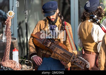 Ein Musiker aus der alten Zeit Matrosen Tuning einer Nyckelharpa am Newquay Orchard Amphitheater in Cornwall. Stockfoto