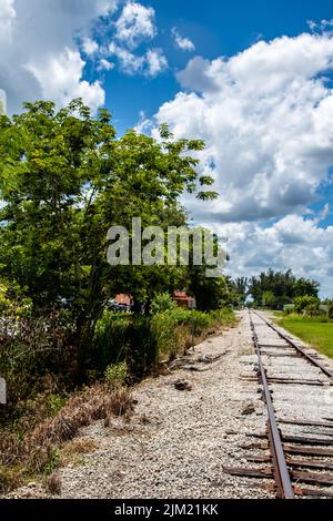 Eisenbahnstrecken in einer verlassenen Landschaft, blauer Himmel mit Wolken oben, vertikale Ausrichtung: Punta Gorda, Florida historisches Wahrzeichen Stockfoto