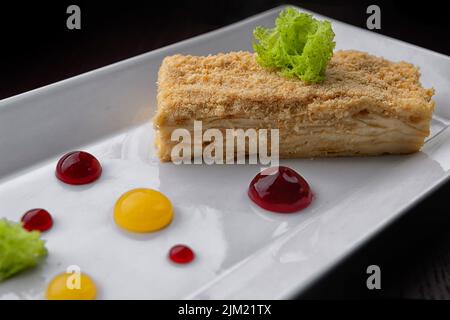 Ein Stück Napoleon-Kuchen Dessert auf einem Teller. Auf schwarzem Hintergrund. Selektiver Fokus Stockfoto