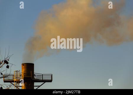 Goiania, Goiás, Brasilien – 04. August 2022: Rauch kommt aus einem Fabrikschornstein. Rauchverschmutzung durch die Fabrik mit dem Himmel im Hintergrund. Stockfoto