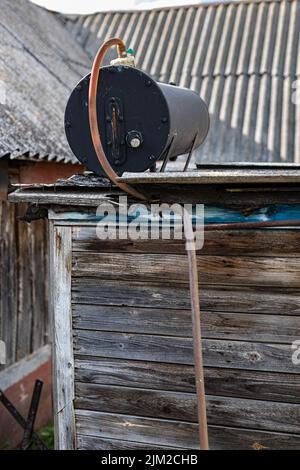 Auf dem Dach einer Sommerdusche im Dorf steht ein alter Heiztank Stockfoto