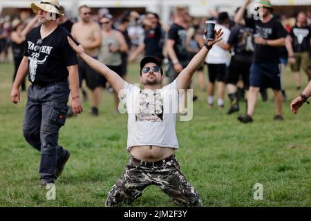 Wacken, Deutschland. 04. August 2022. Ein Mann kniet nach der Eröffnung des Infield auf dem Festivalgelände des Wacken Open Air (WOA). Es gilt als das größte Heavy Metal Festival der Welt. Quelle: Frank Molter/dpa/Alamy Live News Stockfoto