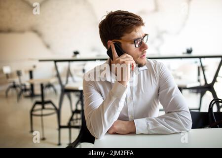 Junger Geschäftsmann, der Kaffee trinken und seine Arbeit im Café verrichten will. Menschen, Erfolg, Arbeitskonzept. Stockfoto