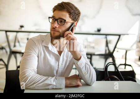 Junger Geschäftsmann, der Kaffee trinken und seine Arbeit im Café verrichten will. Menschen, Erfolg, Arbeitskonzept. Stockfoto