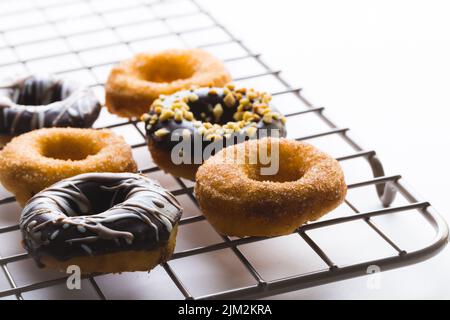 Nahaufnahme von frischen verschiedenen Donuts auf Kühlregal vor weißem Hintergrund Stockfoto