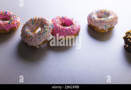 High-Angle-Ansicht von frischen Donuts mit bunten Sprinklern durch Kopierfläche auf farbigem Hintergrund Stockfoto