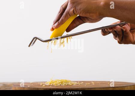 Nahaufnahme eines afroamerikanischen Chefkochs, der Käse auf weißem Hintergrund reissend, Kopierbereich Stockfoto