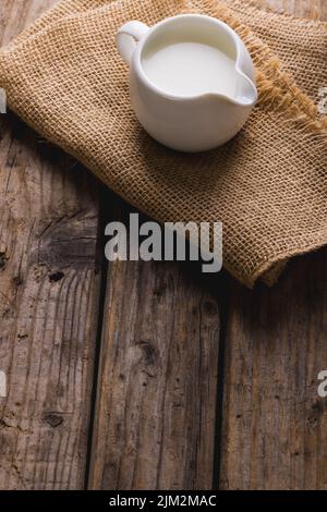 Große Ansicht der Milch im Krug mit Sackleinen auf dem Tisch, Platz zum Kopieren Stockfoto