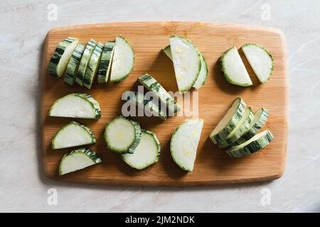 Schneidebrett mit Zucchini in Scheiben geschnitten auf Küchentisch, Tageslicht, Kopierraum Stockfoto