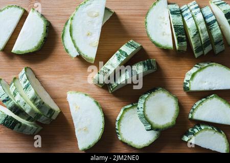 Nahaufnahme von Zucchini in Scheiben geschnitten auf Holzschneidebrett, gute flache Lage Stockfoto