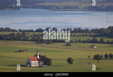 Schwangau, Deutschland. 04. August 2022. Der Forggensee liegt im Sonnenschein hinter der Wallfahrtskirche St. Coloman. Quelle: Karl-Josef Hildenbrand/dpa/Alamy Live News Stockfoto