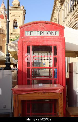 Eine rote britische Telefonbox, die sich zwischen den Telekommunikationsschränken befindet, schafft einen intimen Essbereich mit einem Tisch für zwei Personen. Rufen Sie einfach an, um Service zu bekommen! Stockfoto