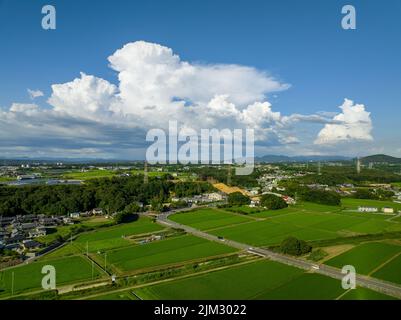 An sonnigen Tagen wabenhafte weiße Wolken über ländlichen Bauernhöfen und Landschaft Stockfoto