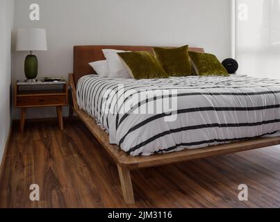 Bettgestell, Schlafzimmer mit Matte auf dem Boden, Tontopf im Hintergrund, Holzcredenza und Spiegel. Der gleiche Holzboden, gemütlicher, moderner Raum, mit Stil Stockfoto