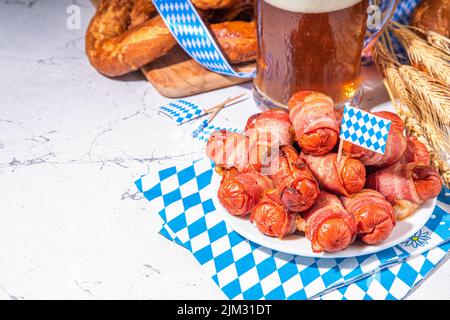 Oktoberfest Party Essen. Brezel-Hotdogs, Blätterteig-Brötchen mit Wurst und Speck, traditionelle bayerische deutsche Schweine in Decke auf Oktoberfest-Decora Stockfoto