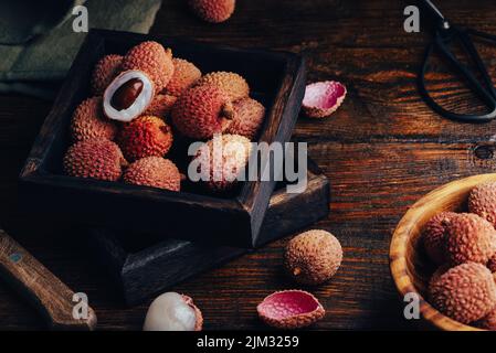 Litchi Früchte in Holzbehälter auf rustikalem Tisch Stockfoto