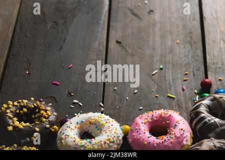 Weitwinkelansicht von frischen verschiedenen Donuts mit Sprinklern auf Holztisch Stockfoto