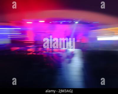 Verwischen Sie die Fluidität der Menschenmassen im Nachtclub. Menschen, die Spaß in Nachtclub Lichter Bokeh Hintergrund. Stockfoto