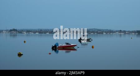 Kurz nach Sonnenaufgang vertäuten Schnellboote auf dem Blackwater im Heybridge Basin, Essex, wobei sich die Boote im Wasser spiegeln Stockfoto