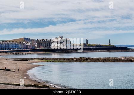 Blick auf den Kiesstrand und den Pier in Cardigan Bay, Aberystwyth. Das Alte College, die Burgruinen und das Kriegsdenkmal sind ebenfalls zu sehen. Stockfoto