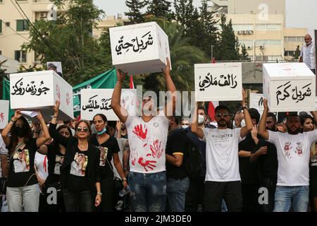 Beirut, Libanon. 04. August 2022. Familien vom 04. August 2020 in Beirut tragen symbolische Särge ihrer Geliebten, die bei der verwüsteten Explosion während einer Scheinbegräbnisprozession anlässlich des 2.. Jahrestages des Vorfalls getötet wurden. Ein Teil von Beirut verwüstete Getreidesilos stürzten während des Jahrestages ein. Quelle: Marwan Naamani/dpa/Alamy Live News Stockfoto