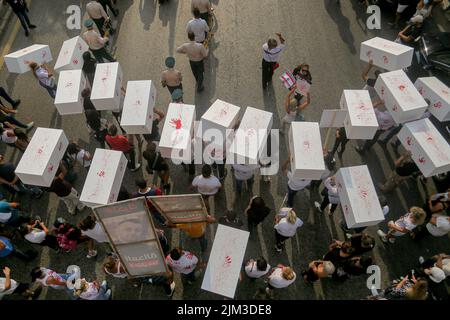 Beirut, Libanon. 04. August 2022. Familien vom 04. August 2020 in Beirut tragen symbolische Särge ihrer Geliebten, die bei der verwüsteten Explosion während einer Scheinbegräbnisprozession anlässlich des 2.. Jahrestages des Vorfalls getötet wurden. Ein Teil von Beirut verwüstete Getreidesilos stürzten während des Jahrestages ein. Quelle: Marwan Naamani/dpa/Alamy Live News Stockfoto