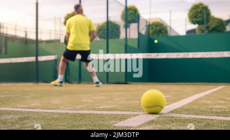 Beobachten Sie die Ausübung des Paddle-Sports auf dem Platz im Freien. Mann, der seinem Schüler Padel-Klasse unterrichtete. Professionelle Trainer, wie Paddel zu spielen. Lernen Sie eine Stockfoto