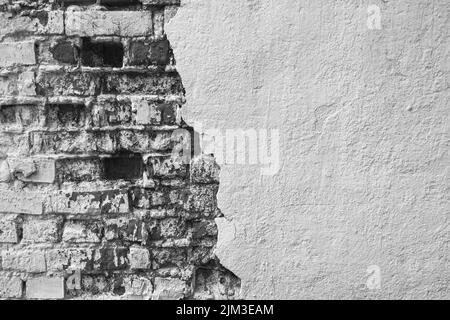 Textur der alten Ziegelwand mit eingestürztem Gips. Hintergrund einer schäbigen Gebäudeoberfläche. Zerstörter Beton und Ziegelwand mit abgefallener Gips. Kopie en Stockfoto
