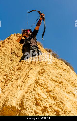 Mann mit Pfeil und Bogen übt Bogenschießen im Park. Stockfoto