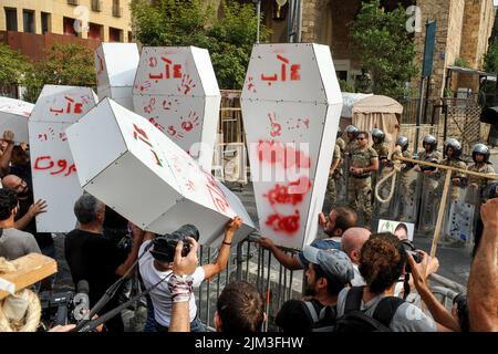 Beirut, Libanon. 04. August 2022. Familien vom 04. August 2020 werfen während eines Protestes zum 2.. Jahrestag des Vorfalls symbolische Särge auf Soldaten, die den Haupteingang des libanesischen parlaments bewachen. Ein Teil von Beirut verwüstete Getreidesilos stürzten während des Jahrestages ein. Kredit: Stringer/dpa/Alamy Live Nachrichten Stockfoto